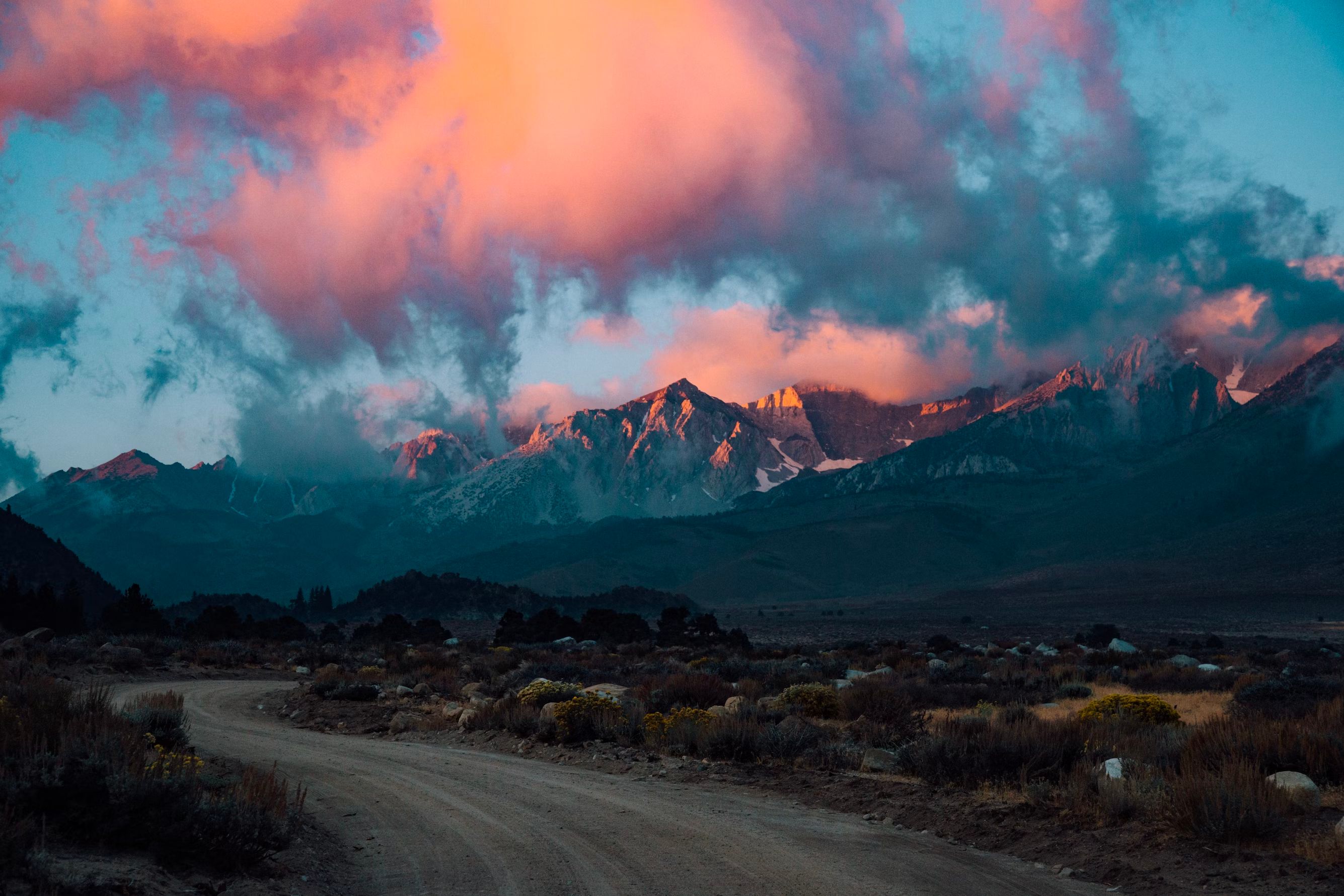 Hiker with headlamp viewing a vibrant night sky atop a rock formation in a place that looks like a national park